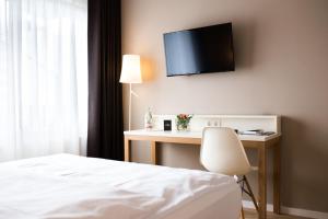 Hotel Krone في Steinenbronn: غرفة نوم مع سرير ومكتب مع تلفزيون على الحائط
