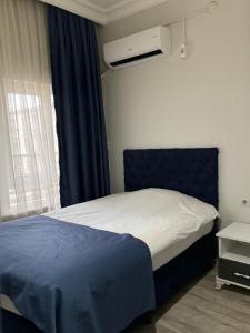 a bedroom with a bed with a blue headboard and a window at Şehir Palas Otel in Mus
