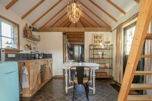 a kitchen with a table and a chandelier at Schaapskooi in Maarsbergen +6 photos