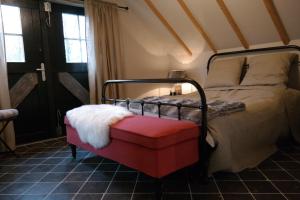 a bedroom with a bed with a red ottoman at Schaapskooi in Maarsbergen