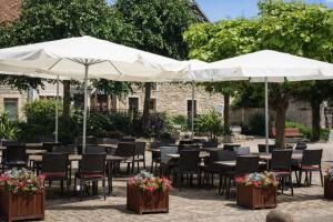a patio with tables and chairs and umbrellas at Relais de Bèze in Bèze