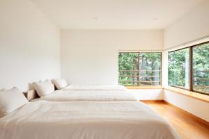 two beds in a white room with a window at 修善寺あざみ Luxury Japanese Villa with Mt Fuji Views and Onsen in Izu