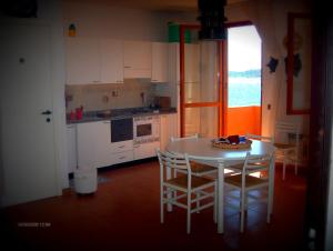 ラ・マッダレーナにあるAppartamento La Maddalenaのキッチン(白いテーブル、椅子付)、窓付きのキッチン