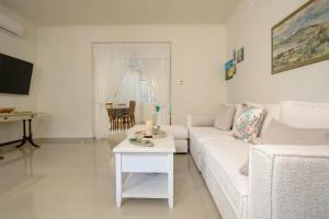a white living room with a white couch and a table at Athenais Two Storey House in Zakynthos