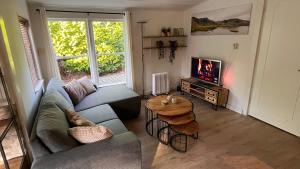 a living room with a couch and a table and a tv at Buitengewoon Beerze in Beerze