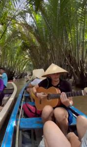 a woman in a hat playing a guitar on a boat at H2T Home in Ho Chi Minh City +9 photos