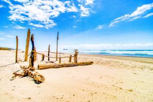a beach with a wooden fence and surfboards on the sand at Sea Treasures Inn Unit #212 in Rockaway Beach +7 photos