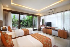 a hotel room with two beds and a television at Putri Ayu Cottages in Ubud