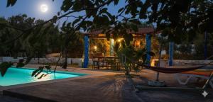 a swimming pool with a hammock and a table at Villa Mabrouka in Raʼs al Jabal