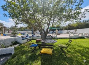 a table and chairs under a tree in a yard at Villa Mabrouka in Raʼs al Jabal