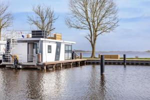 a small house on a dock on a body of water at Welcome in - Houseboat Agua Dolce met tuin, Paviljoenwei 4, Sneek - Offingawier in Offingawier