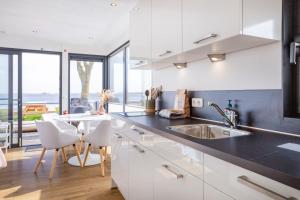 a kitchen with white cabinets and a black counter top at Welcome in - Houseboat Agua Dolce met tuin, Paviljoenwei 4, Sneek - Offingawier in Offingawier