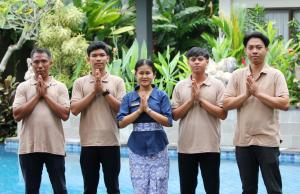 a group of people praying with their hands in front of a pool at Putri Ayu Cottages in Ubud +55 photos