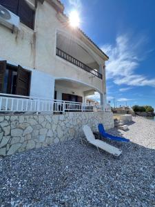 a house with two chairs in front of it at Beachfront summer house in Derveni