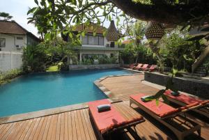 a swimming pool with chairs and a house at Putri Ayu Cottages in Ubud