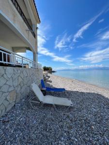 two lounge chairs on a beach next to a building at Beachfront summer house in Derveni