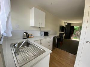 a kitchen with a sink and a microwave at Paraparaumu Motel in Paraparaumu