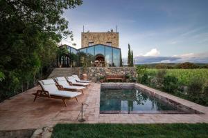 a patio with lounge chairs and a pool in front of a building at Castello Di Vicarello in Sasso dʼOmbrone