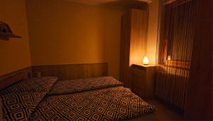a bedroom with a bed with a lamp next to a window at Lotti City Apartman in Békéscsaba