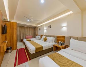a hotel room with two beds and a television at Hotel Kiyara in Kolhapur