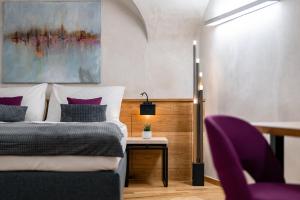 a bedroom with a bed with purple pillows and a table at Hotel Zlaty Andel in Český Krumlov +67 photos