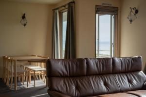a living room with a leather couch and a table at Kaitan稲佐の浜 in Taisha