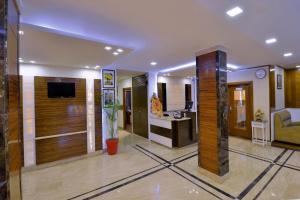 a living room with a television and a living room with a couch at Hotel Mayur by RoomsInc Katra in Katra