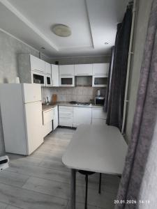 a white kitchen with a table and a white refrigerator at Бухар жырау 45 in Karagandy