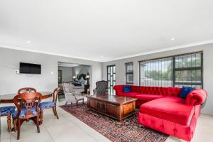 a living room with a red couch and a table at Fair Glen in Kyalami