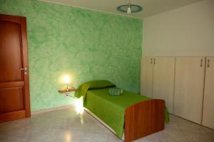 a bedroom with a bed with a green wall at House Gennauara in Lanusei