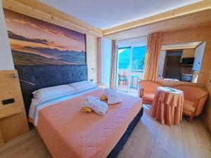 a bedroom with a bed with a painting on the wall at Lake&Nature Hotel Gloria in Molveno +77 photos