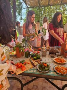 a group of women standing around a table with food at Daba Village in Marrakesh