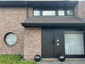 a brick house with a black door and two windows at Steves Place Haasdonk in Beveren