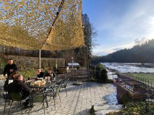 a group of people sitting at a table near a river at Moulin de Nawes in Herbeumont