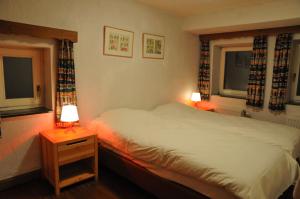 a bedroom with a bed and two windows and two lamps at Moulin de Nawes in Herbeumont