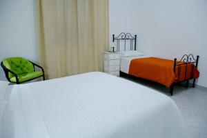 a bedroom with two beds and a green chair at Home's Vita in Trapani