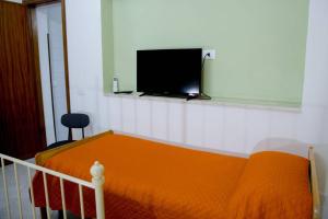 a bedroom with a bed with an orange blanket and a flat screen tv at Home's Vita in Trapani