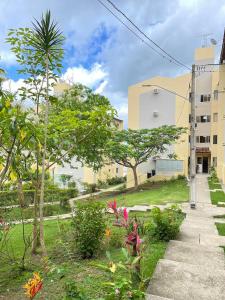 a garden with trees and plants in front of a building at Apartamento moderno com 2 quartos e cama queen-size in Caruaru