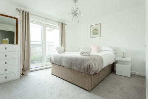 a white bedroom with a bed and a window at Beach Point - Stunning Harbour Views from Balcony in Poole