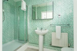 a bathroom with a sink and a shower with a mirror at Beach Point - Stunning Harbour Views from Balcony in Poole