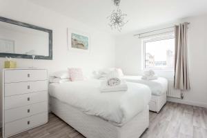 a white bedroom with two beds and a mirror at Beach Point - Stunning Harbour Views from Balcony in Poole