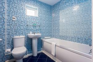 a blue tiled bathroom with a toilet and a sink at Beach Point - Stunning Harbour Views from Balcony in Poole +25 photos
