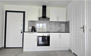 a kitchen with white cabinets and a stove top oven at Le Freneusien, Wi-Fi parking in Freneuse