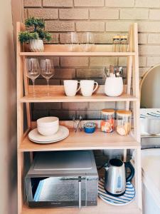 a shelf with dishes and wine glasses and a microwave at Peach Blossom Guesthouse in Welkom