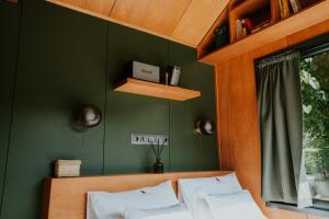 a bedroom with green walls and a bed with white pillows at Feelmore Tiny House Szarvas in Szarvas