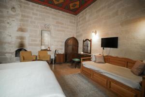 a bedroom with two beds and a desk and a tv at Urgup Konak Hotel in Ürgüp