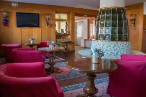 ein Zimmer mit rosa Stühlen und Tischen und einer großen Vase in der Unterkunft Hotel Cristallo in Folgaria
