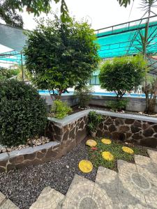 a garden with a stone wall and some trees at Resort safari hot spring in Calamba