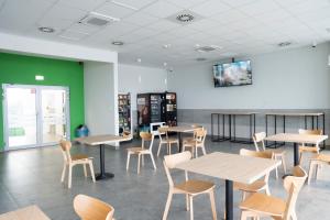 a dining room with tables and chairs and a green wall at Rest&Drive in Warszowice