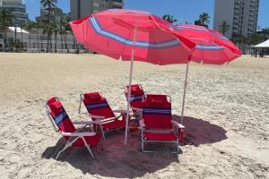 a group of chairs and an umbrella on the beach at Casa Ampla de Praia 2 Piscinas e Ar Condicionado in Matinhos